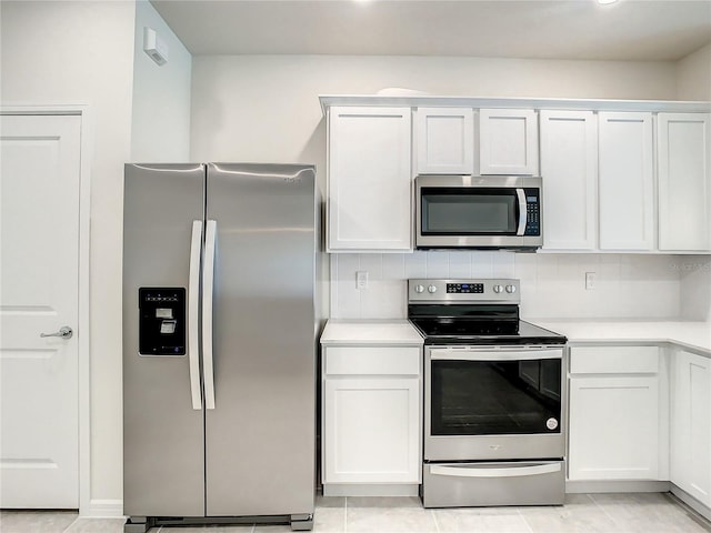 kitchen featuring light tile patterned flooring, white cabinets, stainless steel appliances, and backsplash