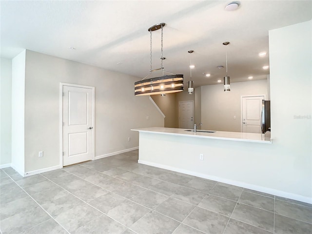 kitchen with light tile patterned floors, stainless steel refrigerator, sink, and pendant lighting