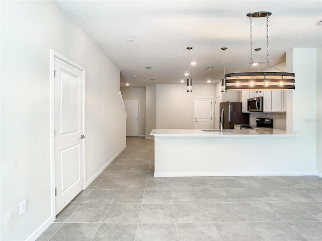 kitchen with appliances with stainless steel finishes, hanging light fixtures, white cabinetry, and light tile patterned flooring