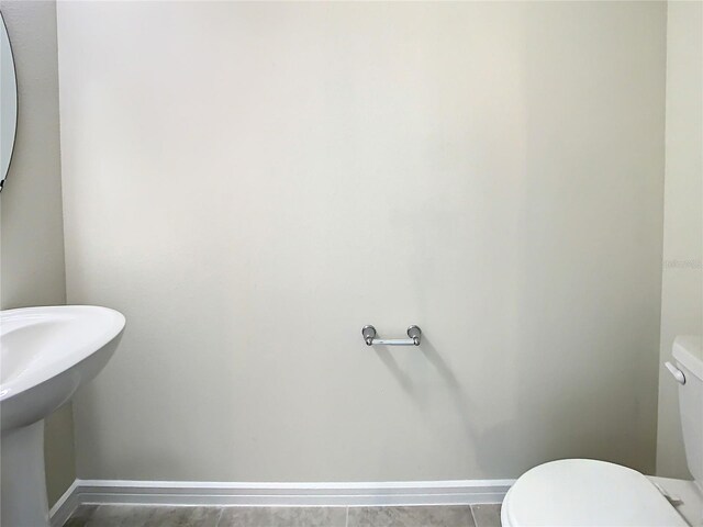 bathroom featuring toilet, tile patterned floors, and sink