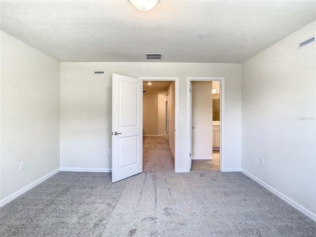 unfurnished bedroom with a textured ceiling and light colored carpet