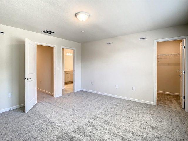 unfurnished bedroom featuring light carpet, a walk in closet, and a closet