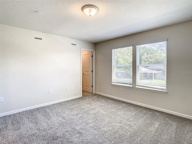 carpeted empty room featuring a textured ceiling