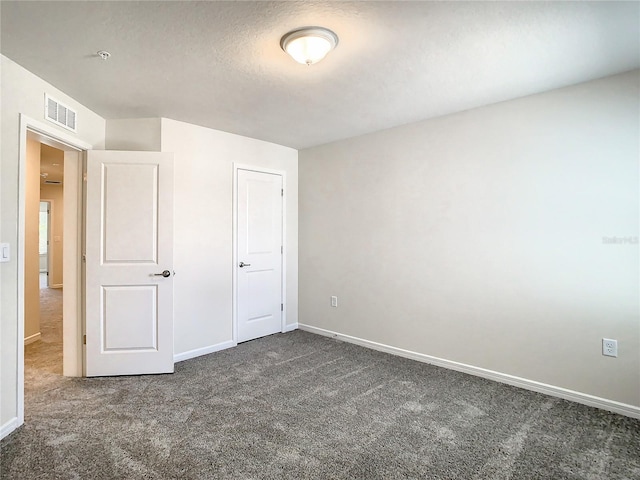 unfurnished bedroom featuring a textured ceiling and dark carpet