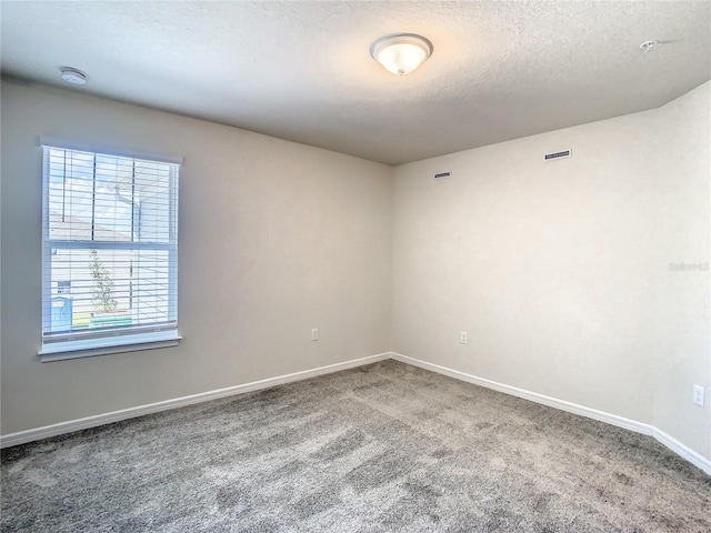 carpeted empty room with a textured ceiling