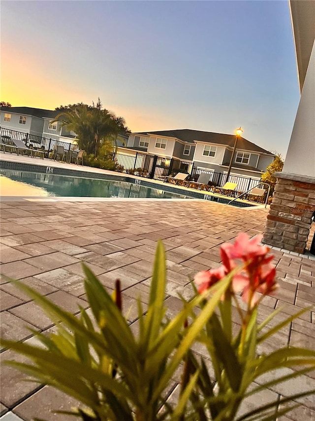 pool at dusk featuring a patio