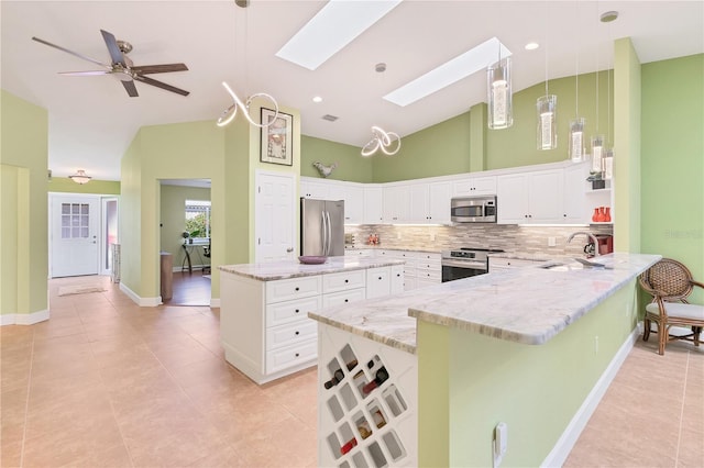 kitchen featuring a skylight, white cabinetry, stainless steel appliances, hanging light fixtures, and a breakfast bar