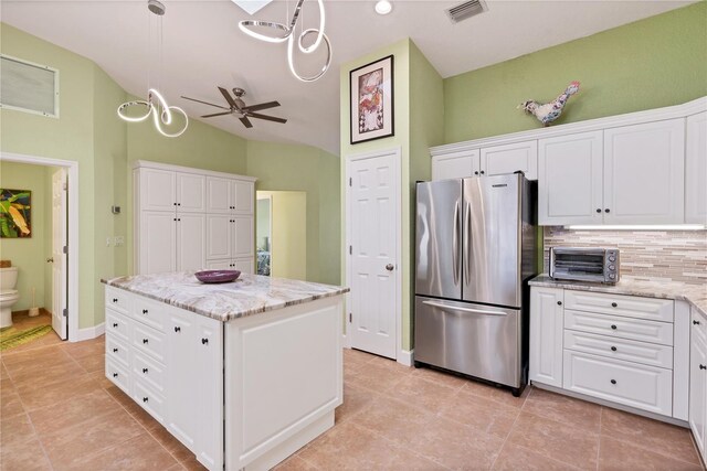 kitchen with a kitchen island, white cabinetry, tasteful backsplash, stainless steel refrigerator, and ceiling fan