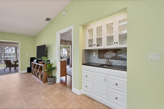 kitchen with white cabinets, lofted ceiling, tasteful backsplash, sink, and light tile patterned flooring