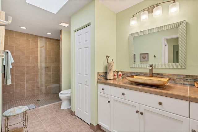 bathroom with toilet, vanity, a skylight, and backsplash