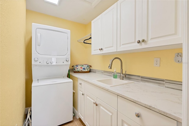 laundry room with stacked washer and dryer, sink, and cabinets