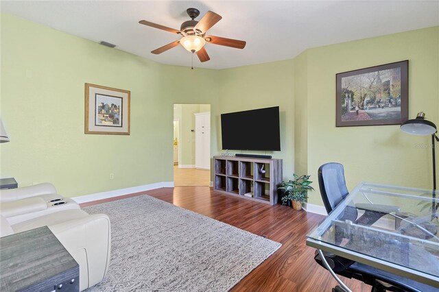 living room featuring ceiling fan and dark hardwood / wood-style flooring