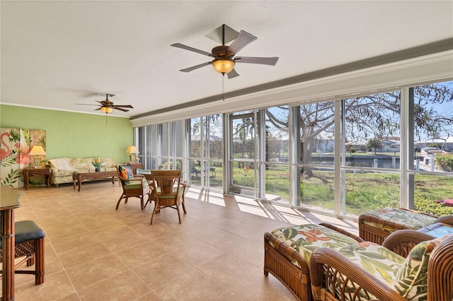 sunroom with ceiling fan and a water view