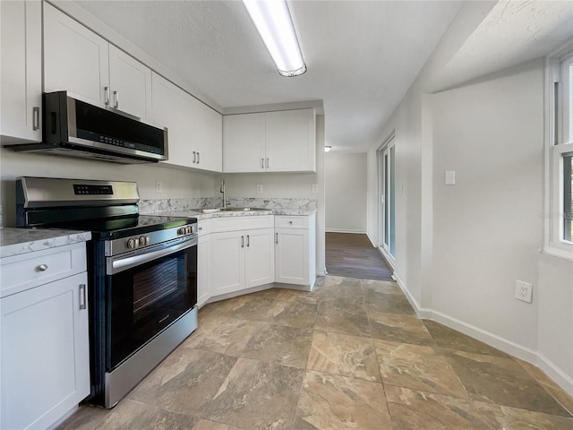 kitchen featuring light stone counters, stainless steel appliances, sink, and white cabinets