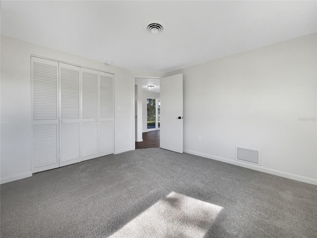 unfurnished bedroom with a closet and dark carpet