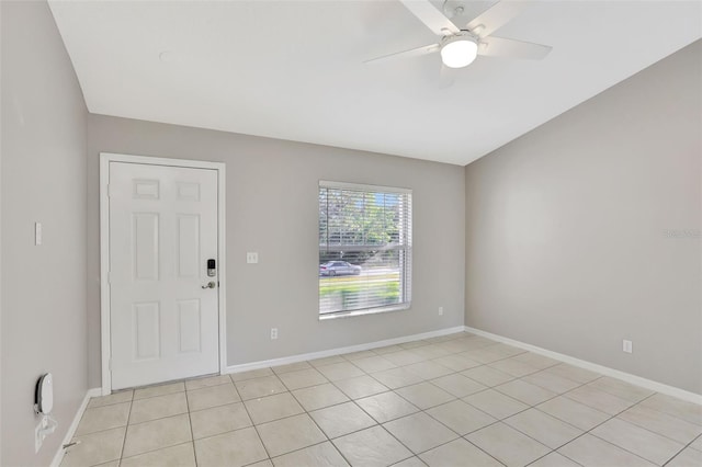 empty room with ceiling fan, vaulted ceiling, and light tile patterned floors