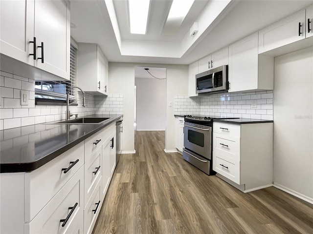 kitchen with dark wood-type flooring, stainless steel appliances, sink, and white cabinets