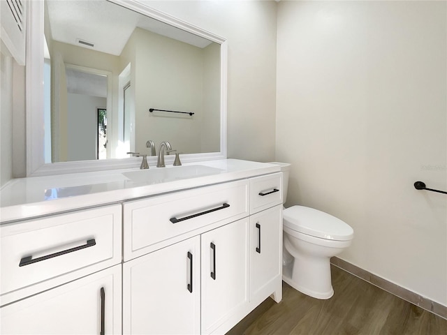 bathroom with toilet, hardwood / wood-style flooring, and vanity