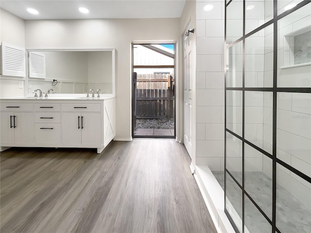 bathroom with vanity, hardwood / wood-style floors, and tiled shower