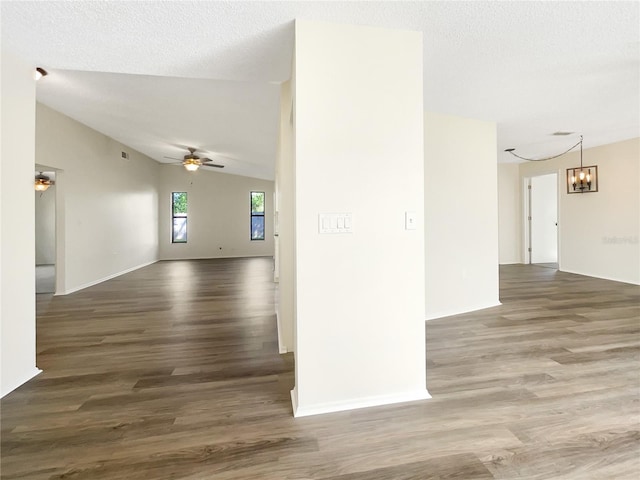 unfurnished room with dark wood-type flooring, vaulted ceiling, a textured ceiling, and ceiling fan with notable chandelier