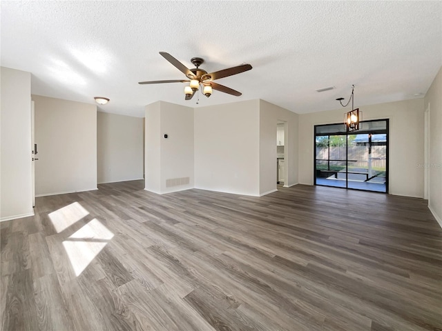 unfurnished room with a textured ceiling, ceiling fan with notable chandelier, and hardwood / wood-style floors