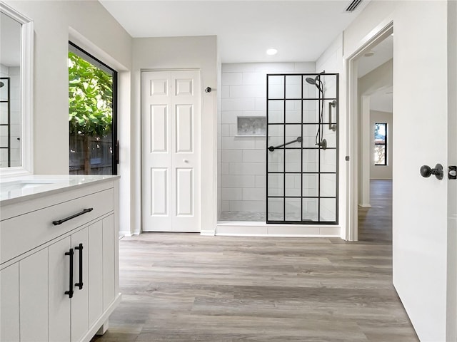 bathroom featuring vanity, a tile shower, and hardwood / wood-style flooring