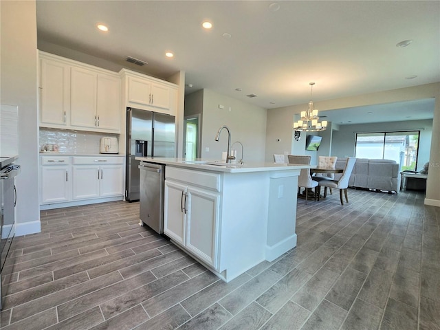 kitchen with a center island with sink, sink, white cabinetry, and hardwood / wood-style floors