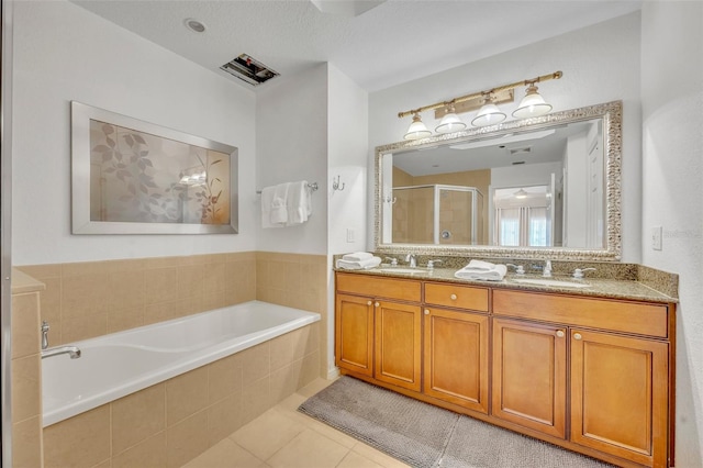 bathroom featuring vanity, a textured ceiling, plus walk in shower, and tile patterned flooring