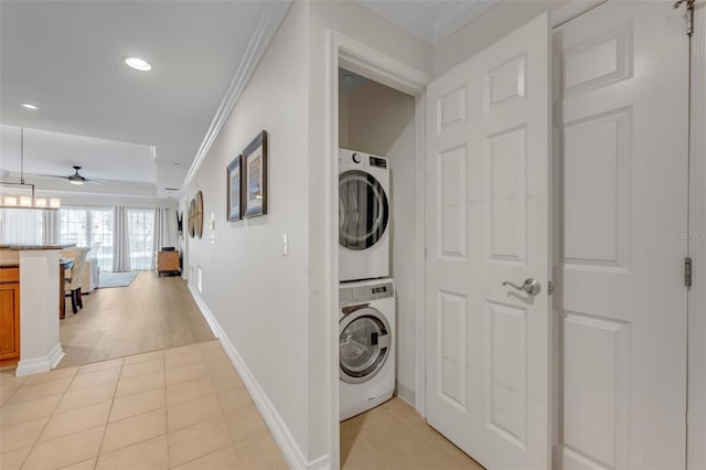 laundry area with stacked washer / dryer, ornamental molding, light tile patterned flooring, and ceiling fan