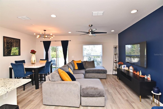 living room with light hardwood / wood-style floors and ceiling fan with notable chandelier