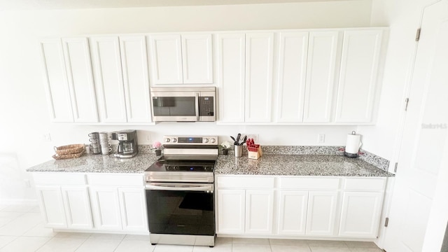 kitchen with appliances with stainless steel finishes, white cabinetry, and light tile patterned floors