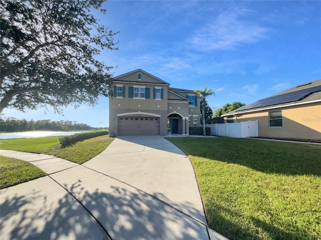 view of front facade with a front lawn, a garage, and a water view