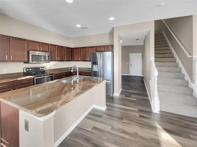 kitchen featuring appliances with stainless steel finishes, a kitchen island with sink, sink, and dark hardwood / wood-style flooring