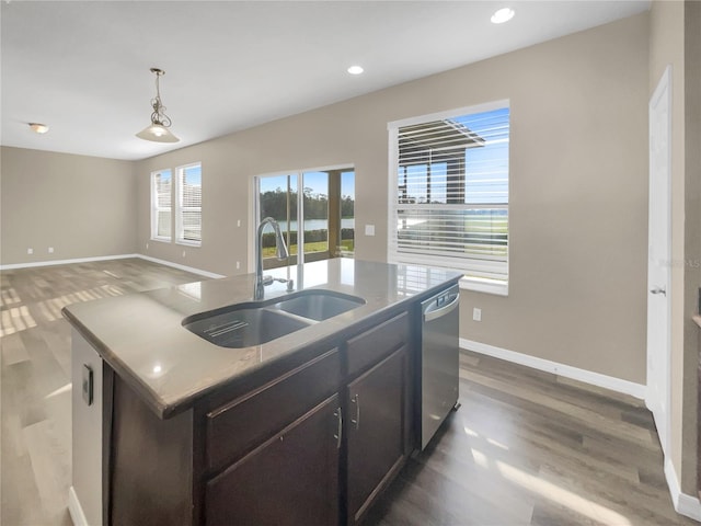 kitchen with hardwood / wood-style floors, hanging light fixtures, a center island with sink, dishwasher, and sink