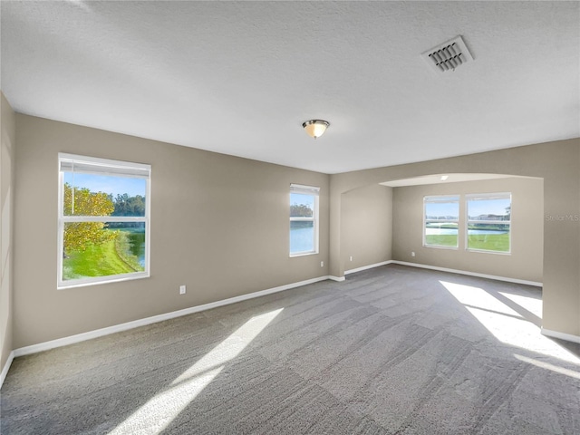 carpeted empty room with a textured ceiling