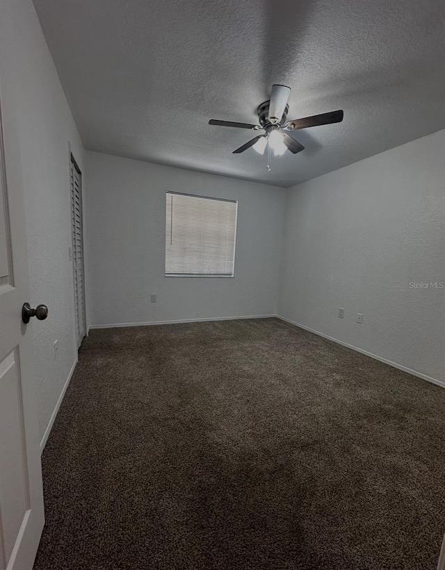 carpeted spare room featuring ceiling fan and a textured ceiling