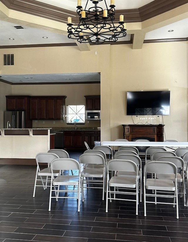 dining room with crown molding, a fireplace, a notable chandelier, dark hardwood / wood-style flooring, and sink