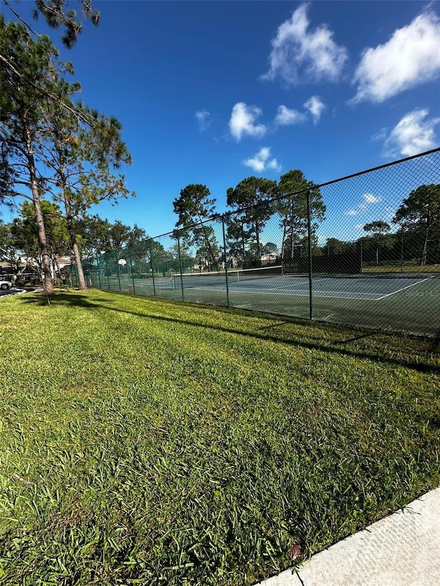 view of tennis court featuring a lawn