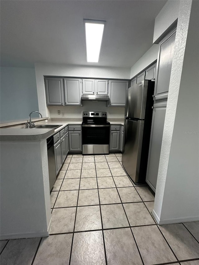 kitchen featuring gray cabinetry, kitchen peninsula, appliances with stainless steel finishes, and light tile patterned flooring