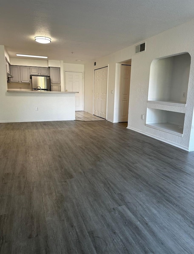 unfurnished living room featuring dark wood-type flooring and a textured ceiling