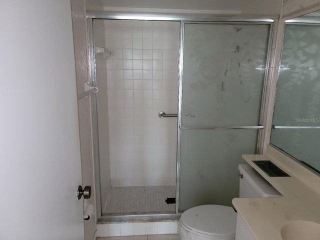 bathroom featuring vanity, toilet, and a shower with shower door