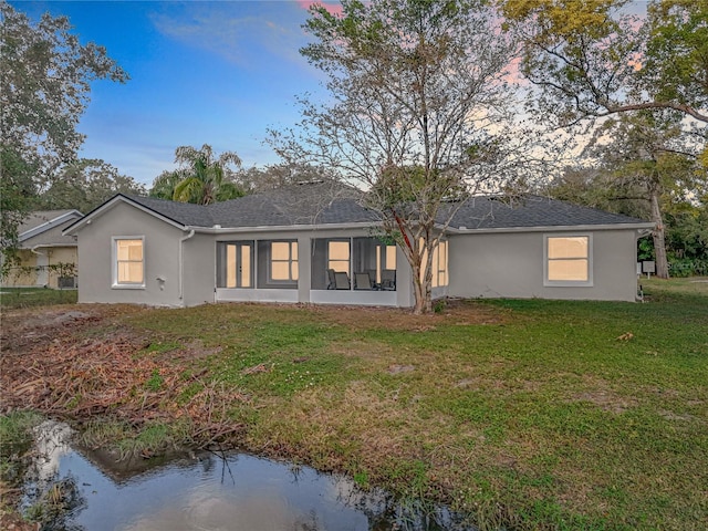 790 Silhouette Ct, Longwood, FL 32750 - back of property at dusk with stucco siding, a lawn, and roof with shingles