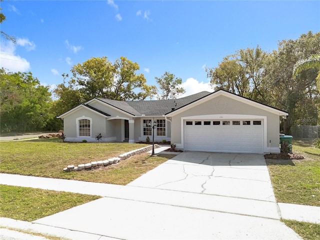 single story home featuring a garage, a front yard, driveway, and stucco siding