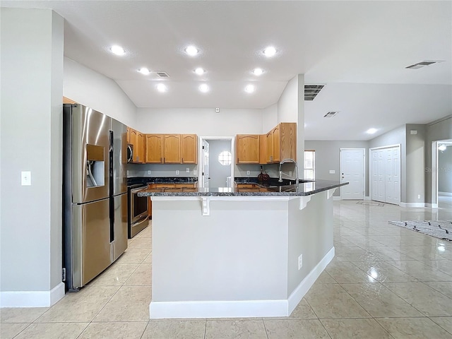 kitchen featuring stainless steel appliances, dark stone countertops, and visible vents