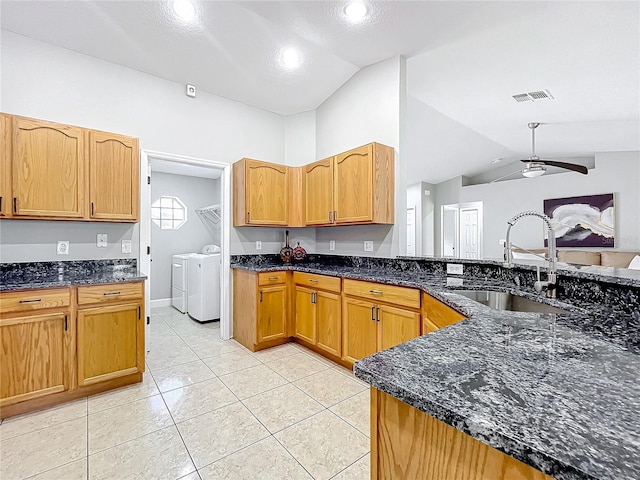 kitchen with lofted ceiling, visible vents, a sink, and washing machine and clothes dryer