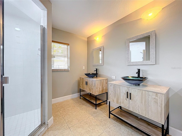 bathroom with baseboards, two vanities, a sink, and a shower stall