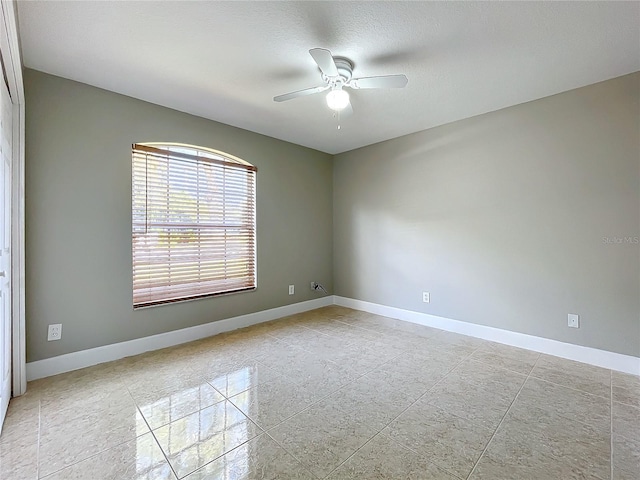 empty room with a ceiling fan, a textured ceiling, and baseboards