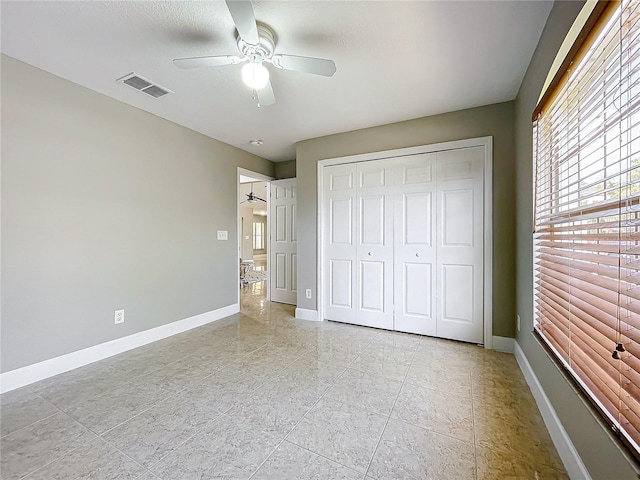 unfurnished bedroom featuring baseboards, visible vents, ceiling fan, and a closet