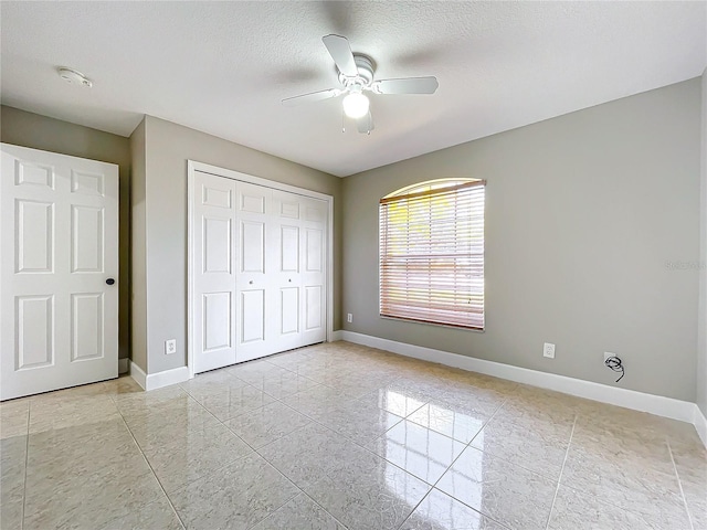 unfurnished bedroom featuring a closet, a textured ceiling, and baseboards