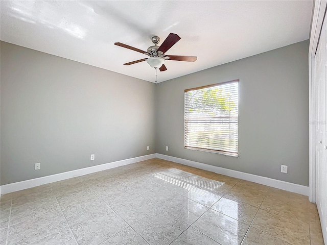 unfurnished room featuring ceiling fan and baseboards